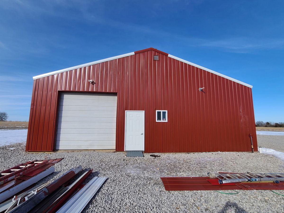 Completed red metal building with garage door in Kansas