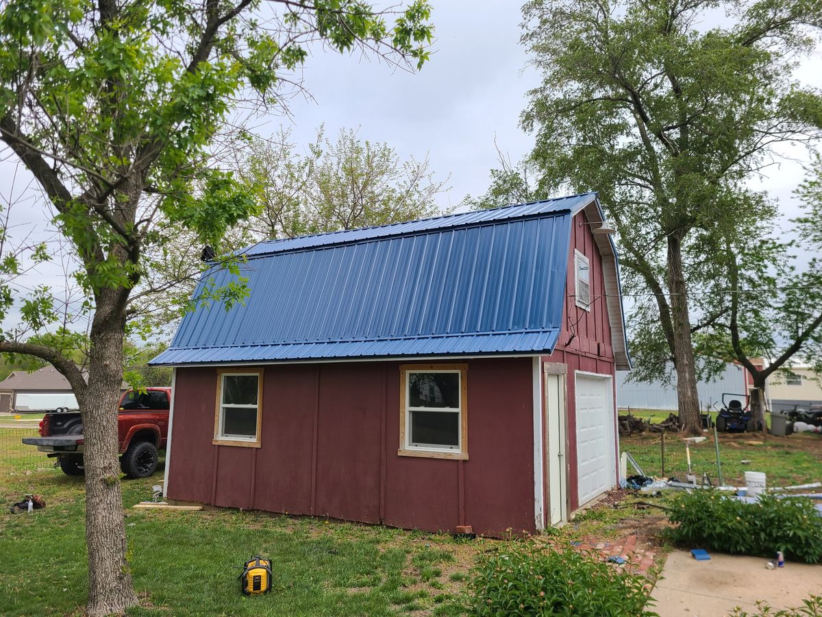 Same red barn with new blue metal roof installed