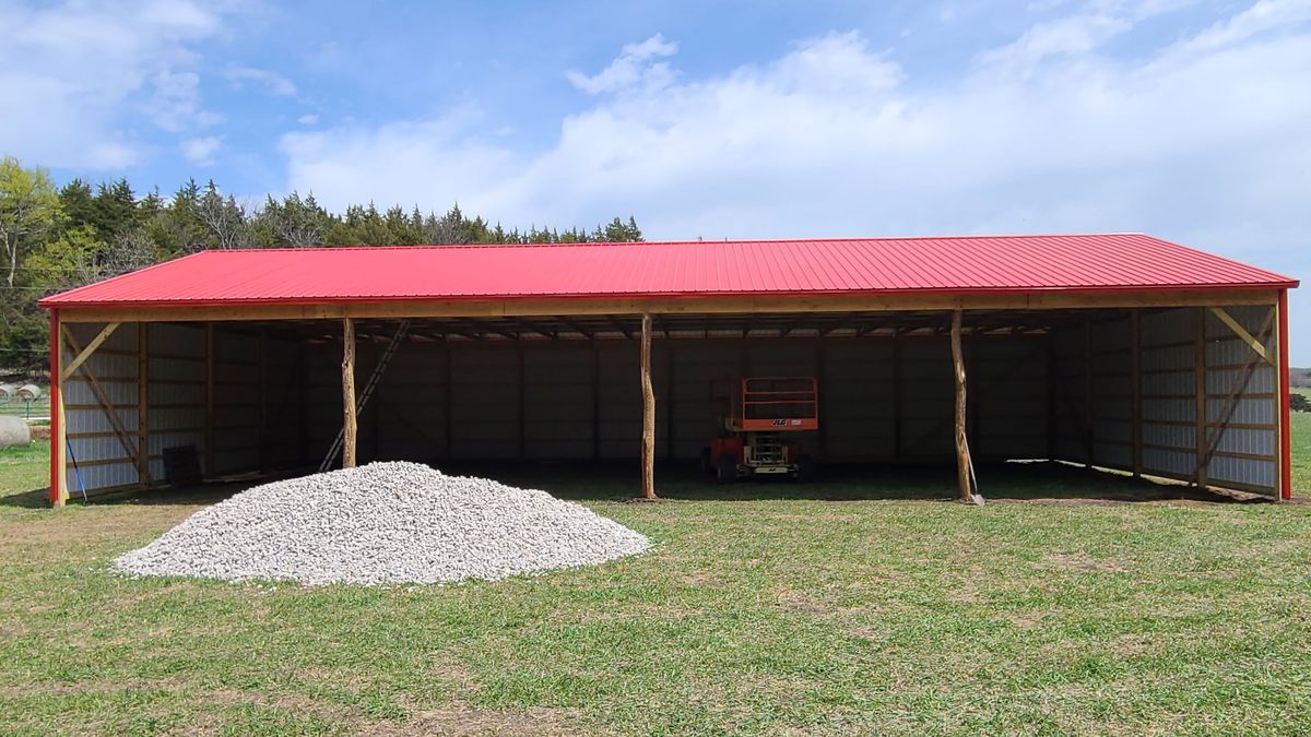 Finished open-front pole barn with red metal roof and siding in Kansas