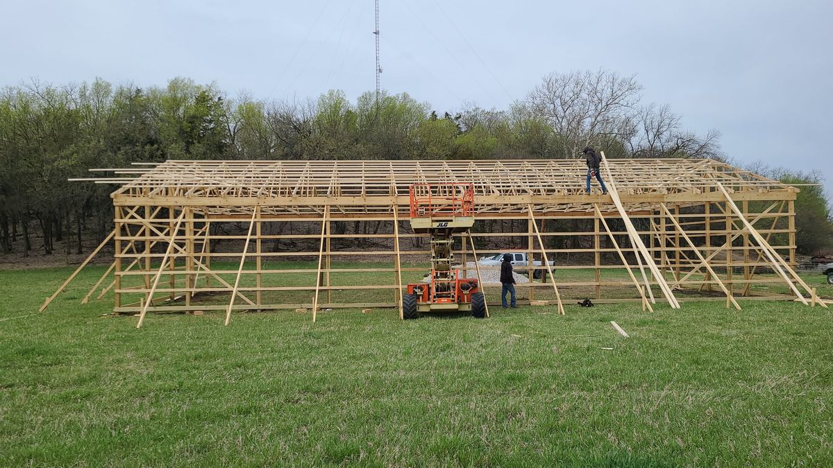 Pole barn framing in progress with crew on lifts in Eastern Kansas